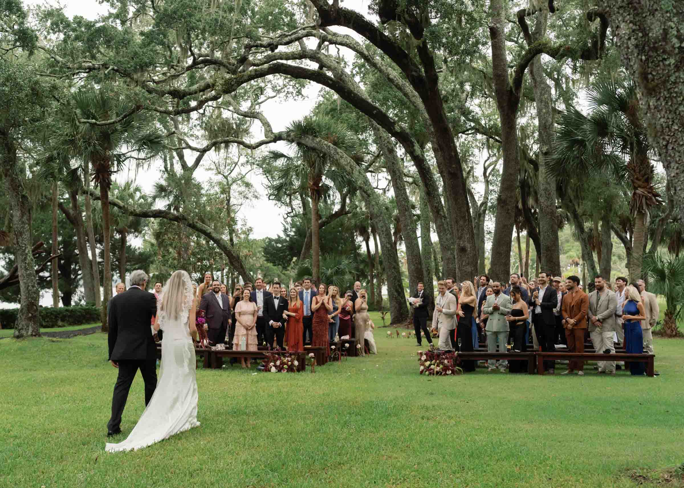 Hilton Head Island Wedding Photogrpaher captures bride walking down the aisle under oak trees.